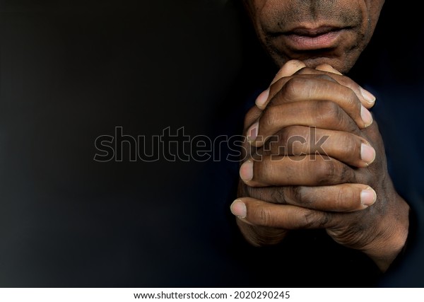 man praying to god
with hands together Caribbean man praying with black background
stock photos stock photo