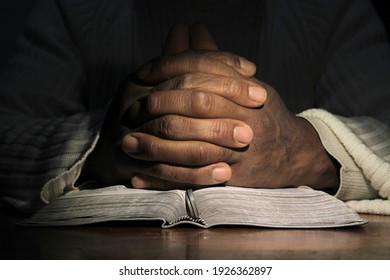 man praying with hand on bible black background stock photo