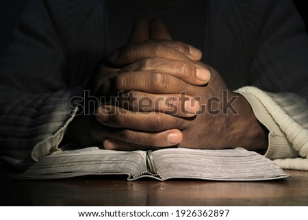 man praying with hand on bible black background stock image stock photo