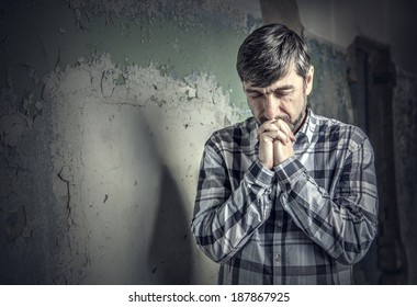 Man Praying On The Background Of Old Wall