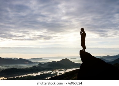 Man praying on cliff against sunrise morning background