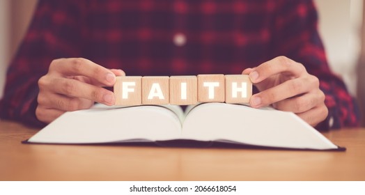 Man praying on holy bible with wooden block word Faith.Worship Faith and Read Bible Online at home.Bible study in home church, wisdom of GOD, Christian Worship and Christian Catholic.Prayer pray.