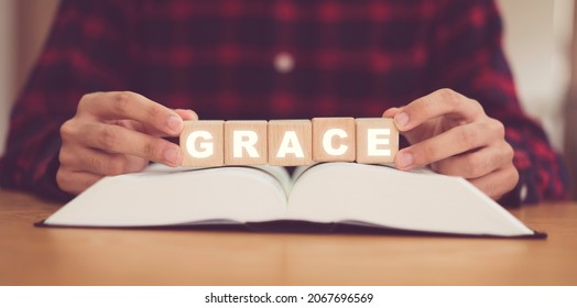 Man praying on holy bible with wooden block word GRACE.Worship Faith and Read Bible Online at home.Bible study in home church, wisdom of GOD, Jesus christ, Easter Worship and Christian.Prayer pray.