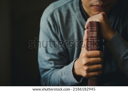 Man praying on the holy bible in the morning. Man hand with Bible praying, Hands folded in prayer on Holy Bible in church concept for faith, spirituality, religion.Christian life crisis prayer to god.