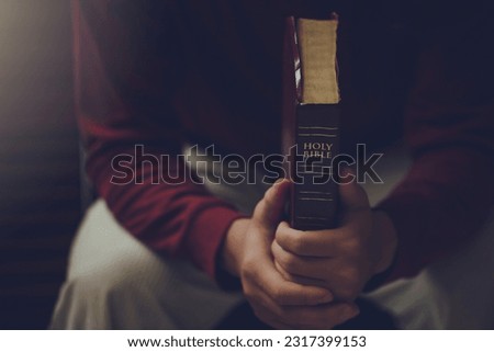  Man praying on the holy bible in the morning. Hands of a Christian man holding a bible while praying to God. spirituality, religion. Christian life crisis prayer to god. believe in goodness.
