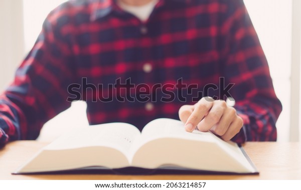 Man praying on holy bible with wooden block word\
bible.Worship Faith and Read Bible Online at home.Bible study in\
home church, wisdom of GOD, Holy spirituality , Worship and\
Christian.Prayer pray.