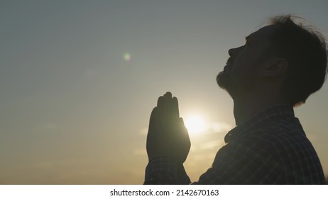 man praying at sunset, asking heaven for help and support, spiritual man contemplating, the concept of faith and hope, reflections in the rays of sunlight, trustworthy religion.