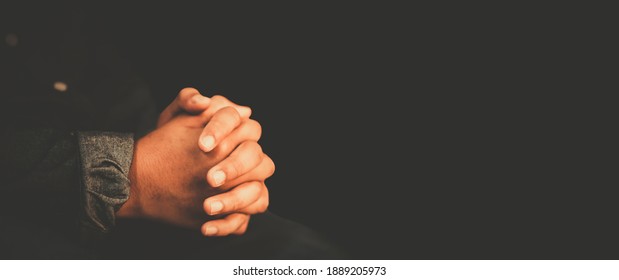 man praying worship at home on black background.Teenager hand praying,Hands folded in prayer.Good friday, Easter, forgiveness.Concept for faith, people, fasting and religion.stay home, lockdown.