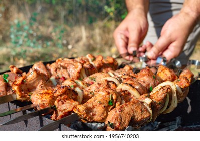 Man Prepare Juicy Slices Of Meat With Sauce On Open Fire. Grilling A Barbecue Outdoors.