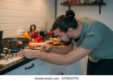 A Man Prepares Breakfast In The Kitchen. Young Handsome Caucasian Male Preparing Food For Himself For Lunch On A Gas Stove In A Large Bright Kitchen