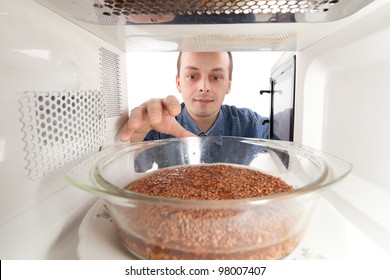 A Man Prepares Buckwheat In The Microwave