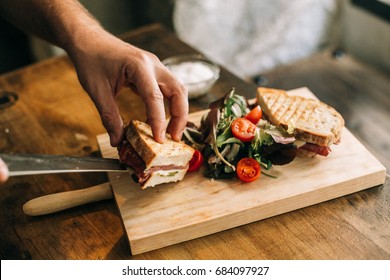 Man Prepares Lunch, Serves Grilled Bread Sandwich Snack On Top Of Wooden Cutting Board, With Side Of Green Salad, Healthy Alternative To Burgers And Grease