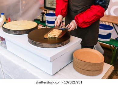 Man Prepares Pancakes On The Stove. A Man Wraps A Stuffed Pancake. Cooking Outside. Chef Bakes Fresh Pancakes