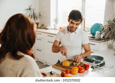 Man Prepares Salad At Home In The Kitchen Next To The Woman. Proper Nutrition And Healthy Eating 