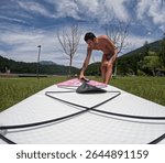 Man is preparing for an excursion with the stand up paddle board in the lake of Levico in Trentino, in Northern Italy- The man is forty years old and is a caucasian with light eyes and hair
