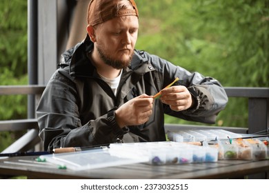 a man preparing for fishing, threads a fishing hook into a rubber bait, fishing, spinning, wobblers, fishing lures - Powered by Shutterstock