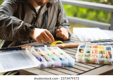 a man preparing for fishing, threads a fishing hook into a rubber bait, fishing, spinning, wobblers, fishing lures - Powered by Shutterstock