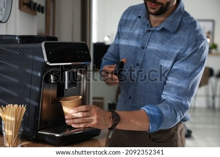 Man preparing fresh aromatic coffee with modern machine in office, closeup