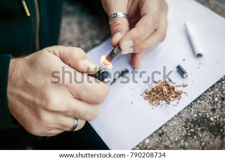 Man preparing hashish joint rolling marijuana cigarette for smoking. Close up