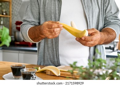 Man preparing healthy breakfast or brunch, peel banana to cut it and put it on puffed corn cakes with smeared peanut butter. Protein diet healthy nutrition concept. Defocused foreground. - Powered by Shutterstock