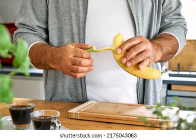 Man preparing healthy breakfast or brunch, peel banana to cut it and put it on puffed corn cakes with smeared peanut butter. Protein diet healthy nutrition concept. - Powered by Shutterstock