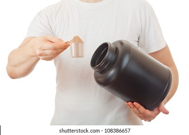 Man Preparing His Post Workout Protein Shake Taking A Scoop Of Chocolate Whey Isolate Powder From The Black Container, Isolated On White