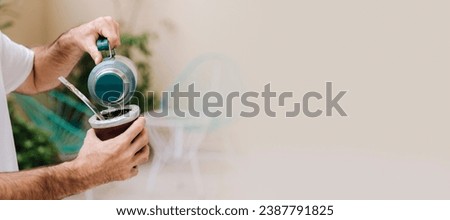 Man preparing a mate with hot water. Gourd mate with yerba inside. Middle age latin american man enjoying at the sunset outdoors. Banner format with copyspace