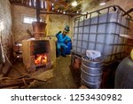 Man preparing plum brandy through boiling and condensation of fruits