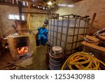 Man preparing plum brandy through boiling and condensation of fruits