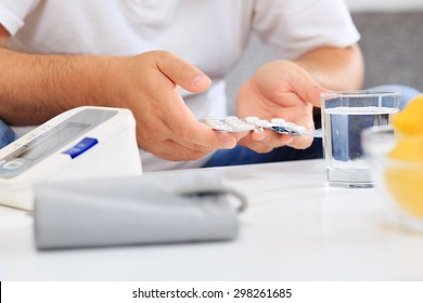 Man Preparing To Take Medication After Blood Pressure Measuring.