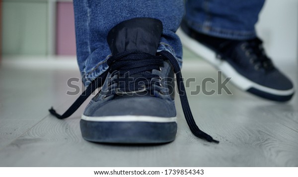 Man Preparing for a Walk with Laces Untied on His\
Sports Shoes\
