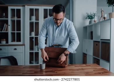 Man preparing for work, closing a leather briefcase in a modern home office, symbolizing professionalism and daily routine