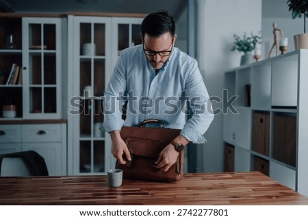 Man preparing for work, closing a leather briefcase in a modern home office, symbolizing professionalism and daily routine