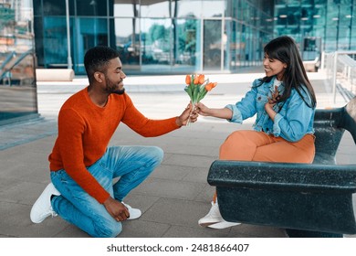 Man Presenting Flowers to Woman Sitting on a Bench in a City Setting - Powered by Shutterstock