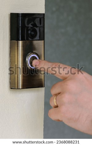 A man presses the button on a "Ring" internet video door-bell from ring.com.