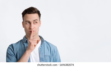 Man presses finger to lips makes silence sign, copy space