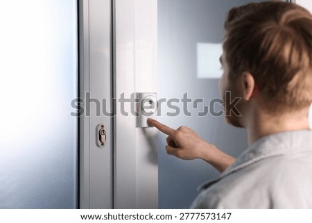 Man pressing button on intercom panel indoors, closeup