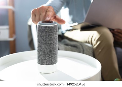 Man Pressing Button On Wireless Speaker At Home