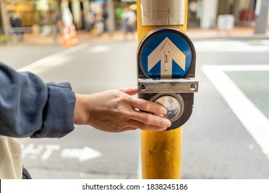 The man pressing a button sign traffic to stop cars before crossing the road in the city,The sign button for pedestrians before a pedestrian crossing.