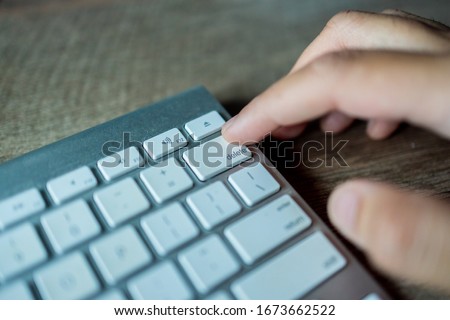 Man pressing delete button on a white metallic keyboard