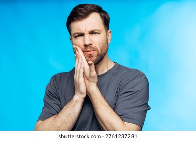 Man pressing his cheek, experiencing intense toothache and dental pain, needing urgent care for oral health issues