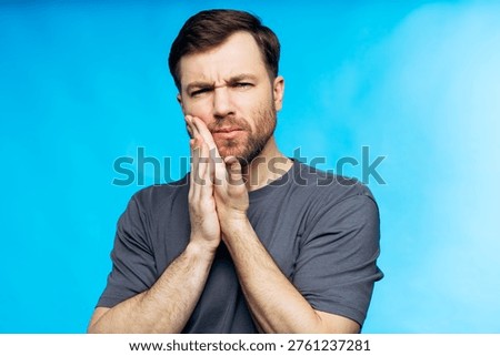 Man pressing his cheek, experiencing intense toothache and dental pain, needing urgent care for oral health issues