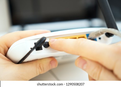 Man Pressing Power Button On The Wifi Router.