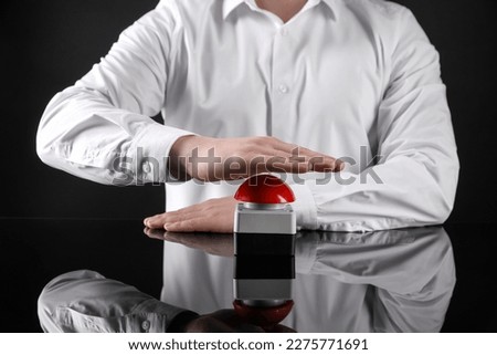 Man pressing red button of nuclear weapon on black background, closeup. War concept