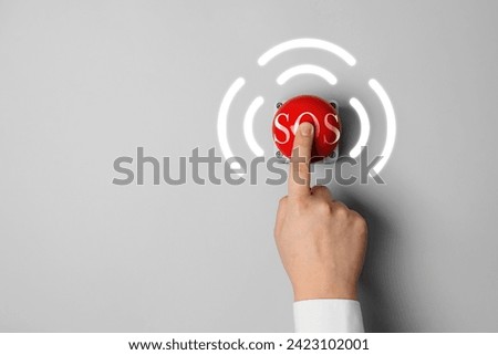Man pressing red SOS button at white background, closeup