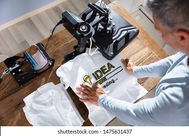 Man Printing Image On T-Shirt In Workshop