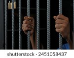 Man in prison hands of behind hold Steel cage jail bars, Male prisoners were severely strained in the dark prison, violence, human trafficking, prison and prisoner concept.