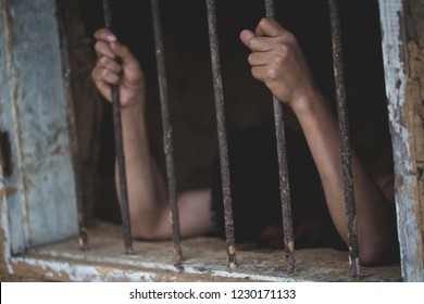 Man in prison hands of behind hold Steel cage jail bars,  Male prisoners were severely strained in the dark prison, violence, human trafficking,  prison and prisoner concept.