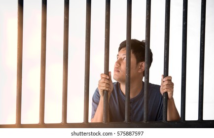 The man of the prisoner on a steel lattice, Man behind jail bars on white background, have sunlight
