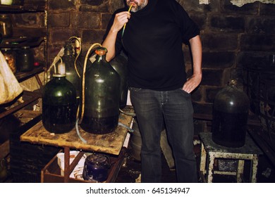 Man In The Private Wine Cellar Next To A Very Large Wine Bottle